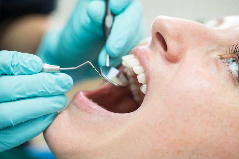 Tandläkare tittar i munnen på en ung tjej